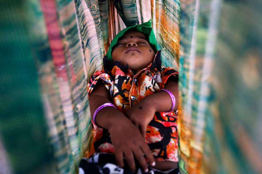 Criança dorme em uma rede enquanto seu pai trabalha em um canteiro de obras em Bengaluru, na Índia - 29/06/2017