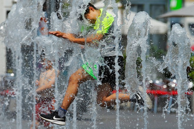 Menino salta através das fontes de água em uma praça pública no primeiro dia do verão em Viena, na Áustria - 21/06/2017