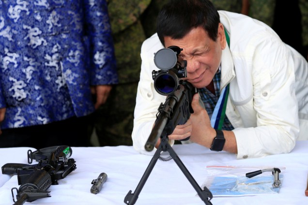 O presidente filipino Rodrigo Duterte verifica o escopo de um rifle durante cerimônia de renovação da assistência militar urgente da China, na Base Aérea de Clark, em Angeles, nas Filipinas - 28/06/2017