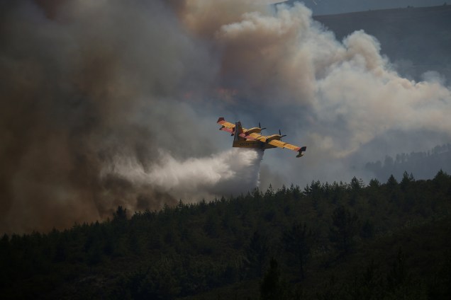 Um avião do corpo de bombeiros de Portugal despeja jatos de água na tentativa de conter as chamas do incêndio florestal em Cadafaz - 20/06/2017