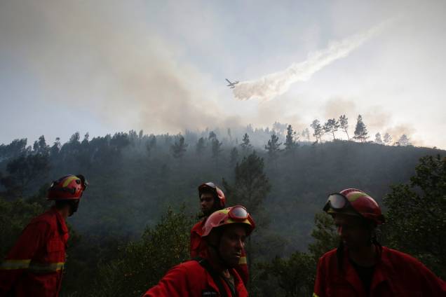 Avião despeja água em um incêndio florestal enquanto bombeiros trabalham no solo em Mendeira, Portugal - 19/06/2017 Avião despeja água em um incêndio florestal enquanto bombeiros trabalham no solo em Mendeira, Portugal - 19/06/2017