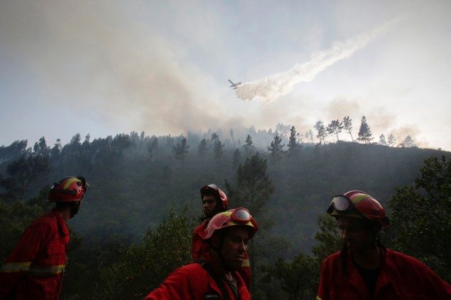 Avião despeja água em um incêndio florestal enquanto bombeiros trabalham no solo em Mendeira, Portugal - 19/06/2017
