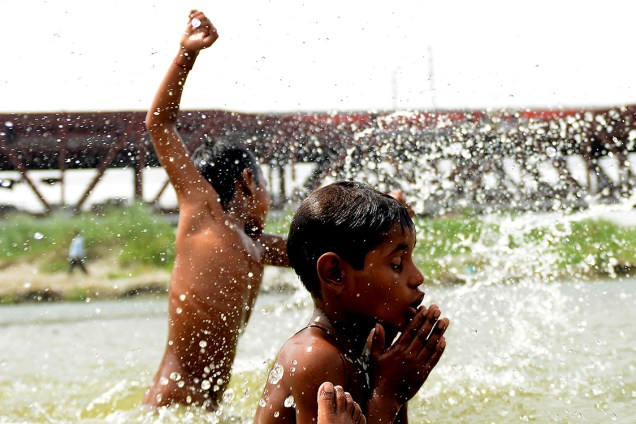 Garotos brincam em um grande lago em Nova Délhi, durante um dia quente com temperaturas registradas acima de 40 graus Celsius, na Índia - 05/06/2017