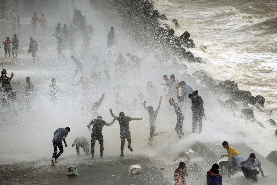 Pessoas se reúnem na estrada a beira mar Marine Drive,  para sentir a água das ondas quebrando, em Mumbai na índia - 28/06/2017
