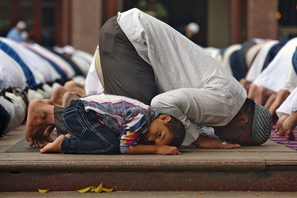 Jovem muçulmano acompanha familiares durante orações em uma mesquita na cidade de Bengaluru, na Índia