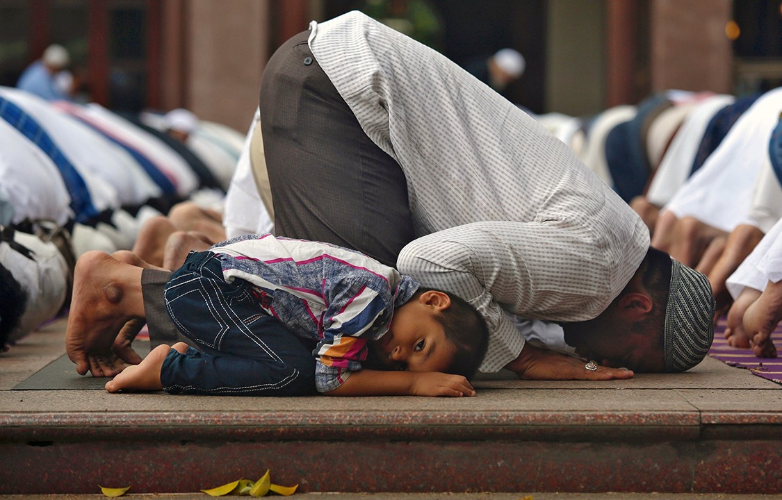 Jovem muçulmano acompanha familiares durante orações em uma mesquita na cidade de Bengaluru, na Índia