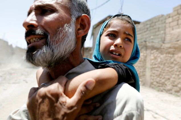 Homem carrega sua filha nas costas depois de fugir de sua casa devido aos combates entre as forças iraquianas e jihadistas do Estado islâmico no distrito de al-Zanjili em Mosul, no Iraque - 07/06/2017