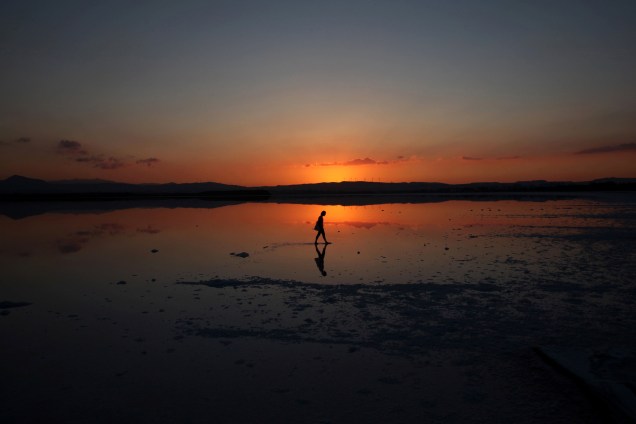 Turista caminha durante o por do sol em um lago em Larnaca, no Chipre - 19/06/2017