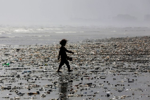 Menina é fotografada em meio ao lixo deixado pelas ondas ao longo da praia de Clifton, em Karachi, no Paquistão  - 21/06/2017