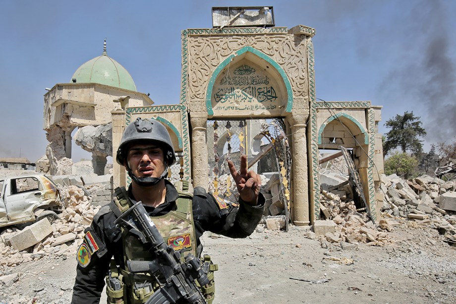 Membro do Esquadrão Anti-Terrorismo do Iraque posa para foto em frente a uma mesquita destruída na Cidade Velha de Mosul - 30/06/2017