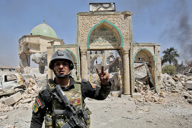 Membro do Esquadrão Anti-Terrorismo do Iraque posa para foto em frente a uma mesquita destruída na Cidade Velha de Mosul - 30/06/2017