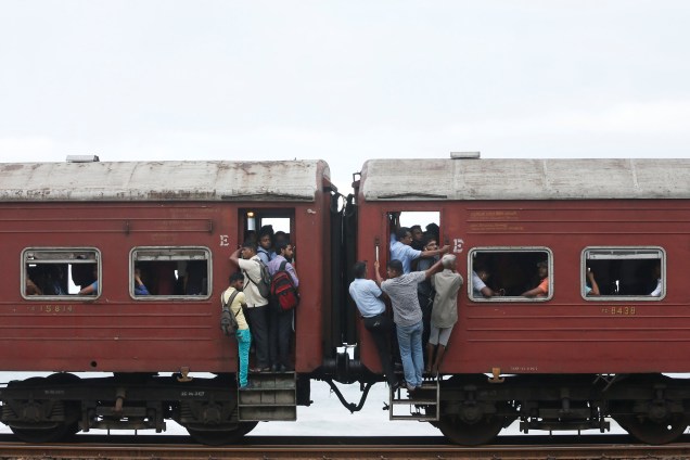 Pessoas viajam penduradas em um trem lotado para chegar ao trabalho em Colombo, no Sri Lanka - 14/06/2017