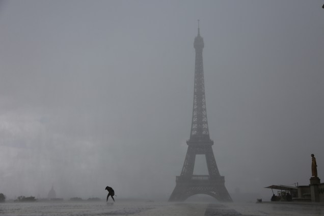 Pessoas correm para se proteger de uma forte chuva na Praça do Trocadero, em frente à Torre Eiffel em Paris, na França - 06/06/2017