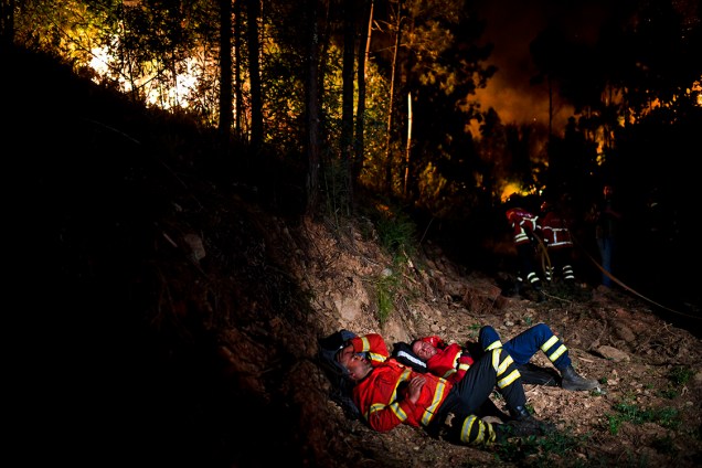 Bombeiros descansam após tentativa de apagar incêndio que atingiu uma floresta próxima a Penela, em Coimbra, deixando pelo menos 62 mortos - 18/06/2017