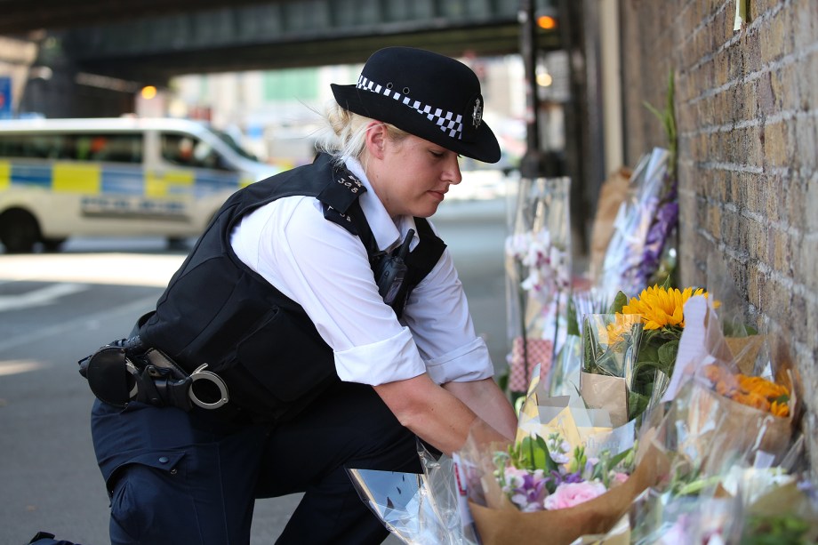 Uma policial deixa flores à vítima de atropelamento em Finsbury Park - 19/06/2017