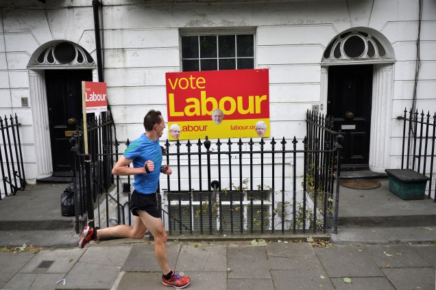 Homem passa em frente às propagandas de Jeremy Corbyn durante sua corrida.