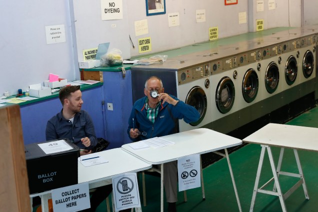 A presiding officer (R) and poll clerk wait for early morning voters at a Polling Station set up in a launderette and nail bar in Headington outside Oxford, west of London, on June 8, 2017, as Britain holds a general election.                                                                              As polling stations across Britain open on Thursday, opinion polls show the outcome of the general election could be a lot tighter than had been predicted when Prime Minister Theresa May announced the vote six weeks ago. / AFP PHOTO / Adrian DENNIS