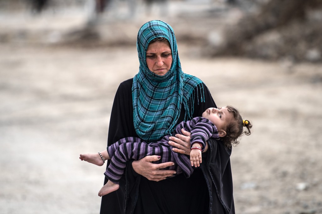 Mulher carrega sobrinha para centro de distribuição de alimentos instalado em Mosul após investida do exército iraquiano contra o Estado Islâmico