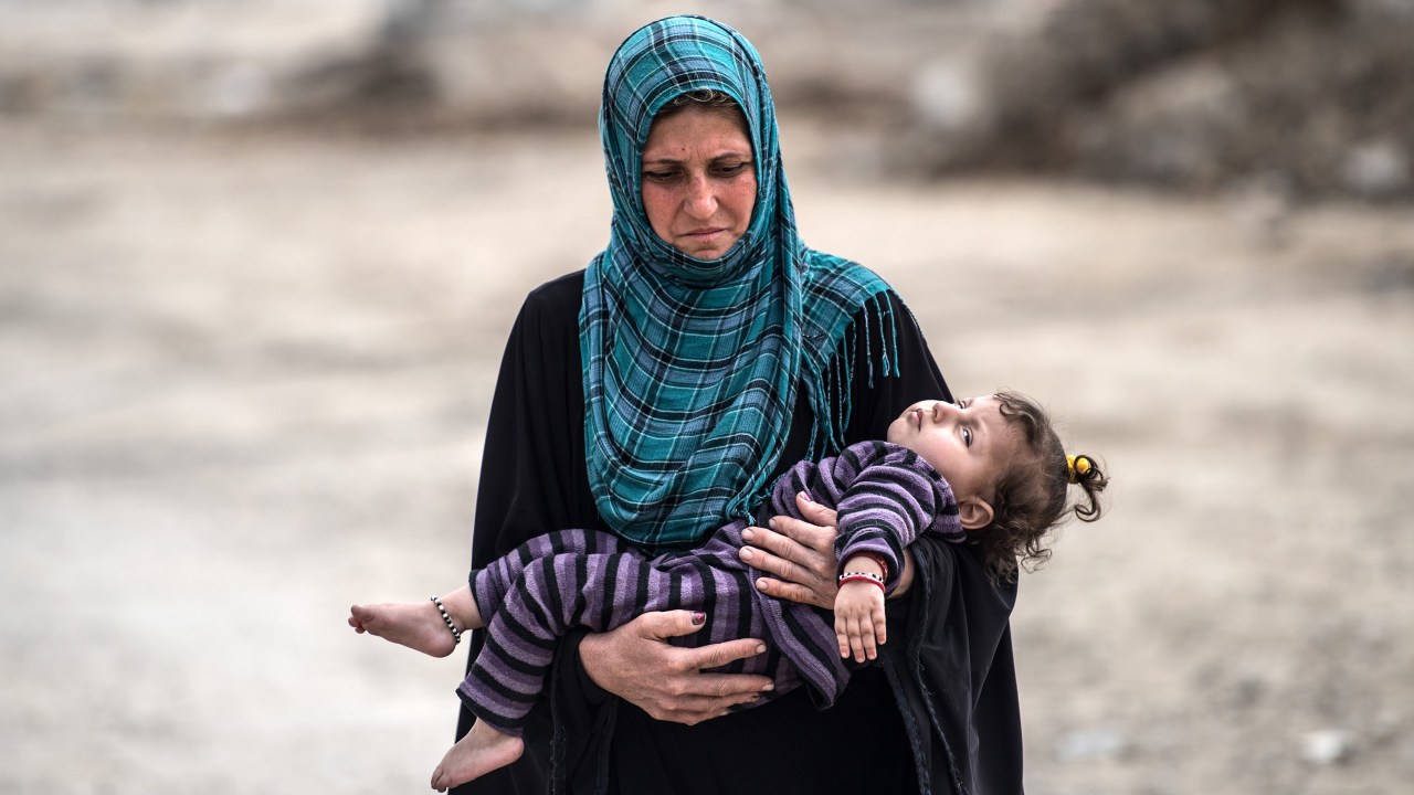 Mulher carrega sobrinha para centro de distribuição de alimentos instalado em Mosul após investida do exército iraquiano contra o Estado Islâmico