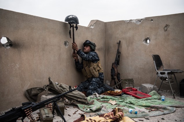 Soldado iraquiano utiliza capacete como armadilha para que um franco-atirador do Estado Islâmico revele sua posição em Mosul, no Iraque
