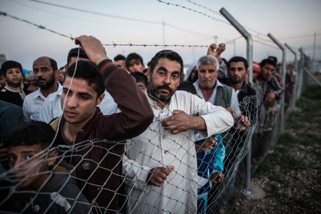 Refugiados aguardam a chamada de seus nomes por um oficial do campo que supervisiona a entrada para as áreas reconquistadas de Mosul.