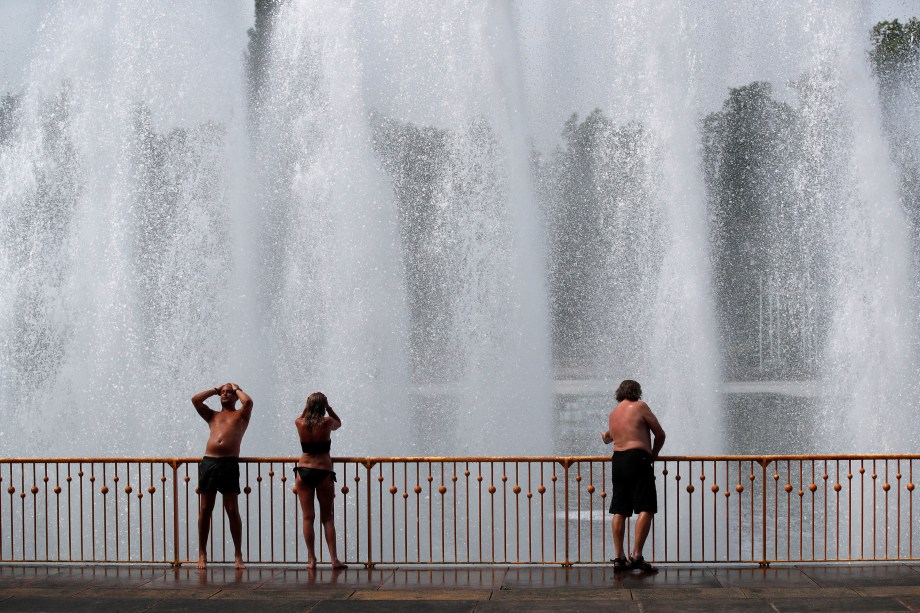 Pessoas desfrutam da água na fonte do parque Battersea, em Londres, para se refrescar durante a onda de calor na europa - 21/06/2017
