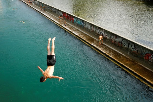 Homem salta de uma ponte direto para o rio Limmat, aproveitando as altas temperaturas do verão europeu, em Zurich na Suíça - 21/06/2017