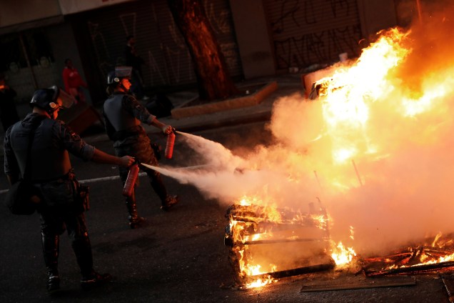 Policiais apagam barricada em chamas feita por manifestantes durante protesto contra as reformas econômicas propostas pelo presidente Michel Temer nesta manhã em São Paulo.