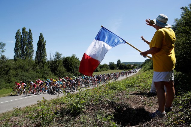 Torcedor segura bandeira da França enquanto o pelotão participa da etapa 6 de 216 km de Vesoul para Troyes, do Le Tour de France - 6 de julho de 2017