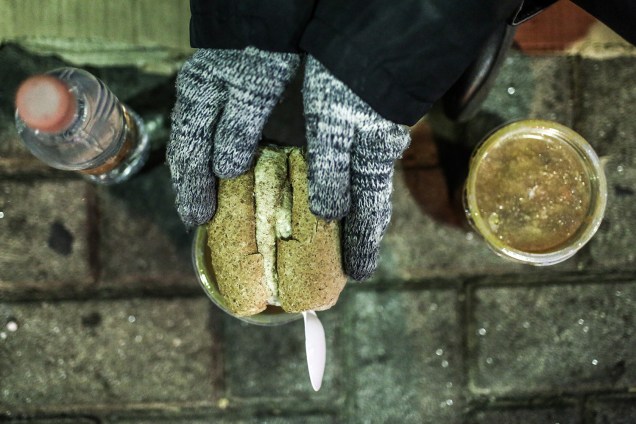 Morador de rua se alimenta com sopa distribuída por voluntários, na região central de São Paulo