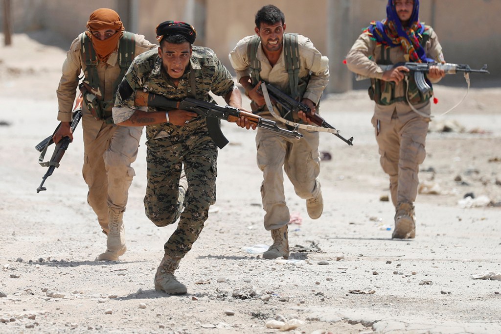 Membros do exército curdo correm em busca de abrigo durante conflito em Raqqa, na Síria