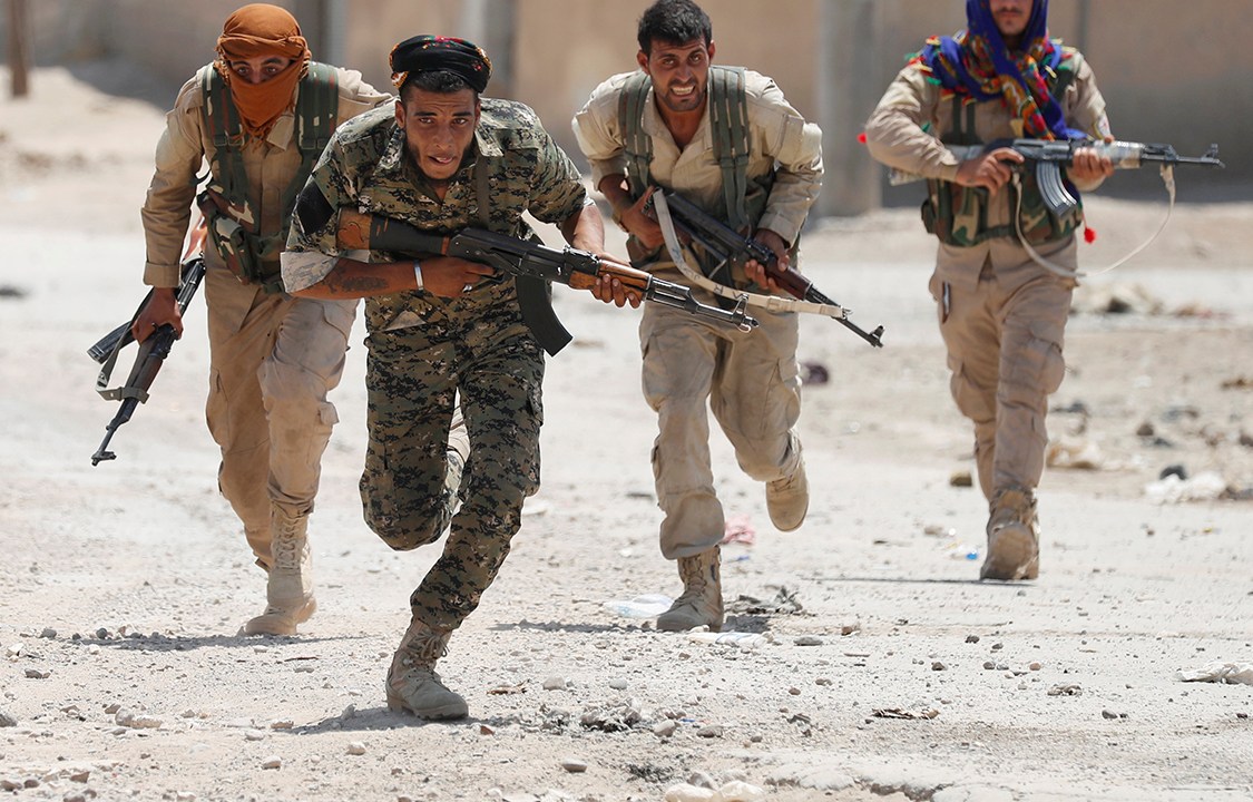Membros do exército curdo correm em busca de abrigo durante conflito em Raqqa, na Síria