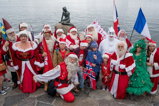 Pessoas vestidas à caráter para o Congresso Mundial de Papais Noéis são fotografadas em frente a estátua da pequena sereia em Copenhague, na Dinamarca