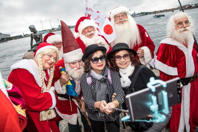Turistas tiram selfie com os membros do Congresso Mundial de Papais Noéis, em frente a estátua da pequena sereia na capital da Dinamarca