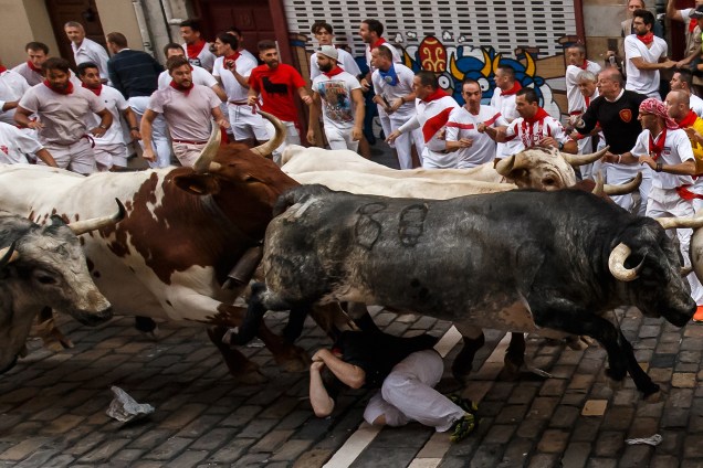 Um corredor cai e acaba embaixo dos touros durante o primeiro dia da corrida no Festival de São Firmino, em Pamplona, norte da Espanha