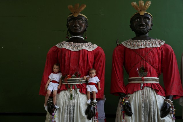 Crianças posam para foto ao lado de dois gigantes durante a "Comparsa de gigantes y cabezudos" do festival de São Firmino em Pamplona, no norte da Espanha.