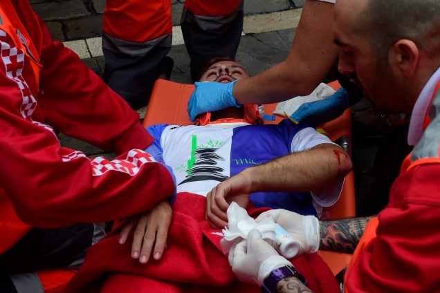 Assistentes médicos ajudam um participante do Festival de São Firmino ferido após a quarta corrida de touros em Pamplona