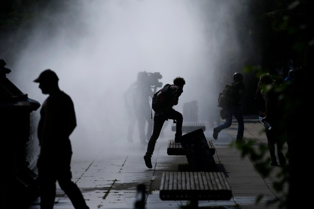 Manifestantes se dispersam ao serem atingidos por jatos de água dos caminhões da polícia alemã durante protesto contra a conferência do G20 em Hamburgo, na Alemanha.