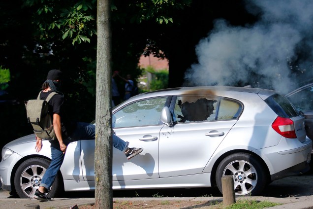 Manifestante chuta um carro durante protesto contra a conferência do G20 na Alemanha.
