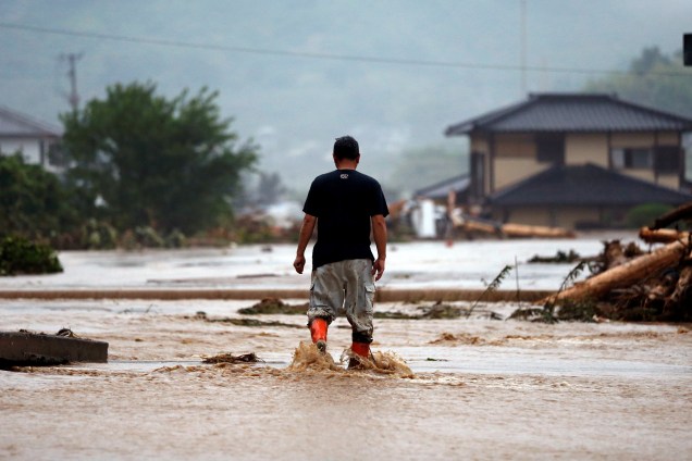Um residente de Asakura caminha pelas ruas inundadas por um rio depois da tempestade em Prefeitura de Fukuoka, no Japão.