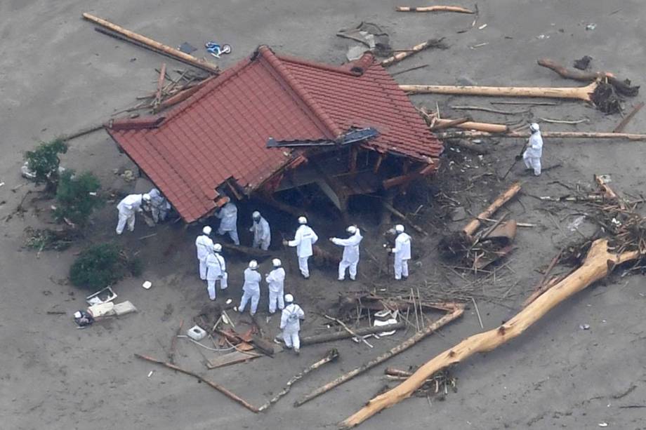 Trabalhadores de resgate são fotografados em uma casa danificada por um rio após fortes chuvas na área, em Asakura, Prefeitura de Fukuoka, Japão.