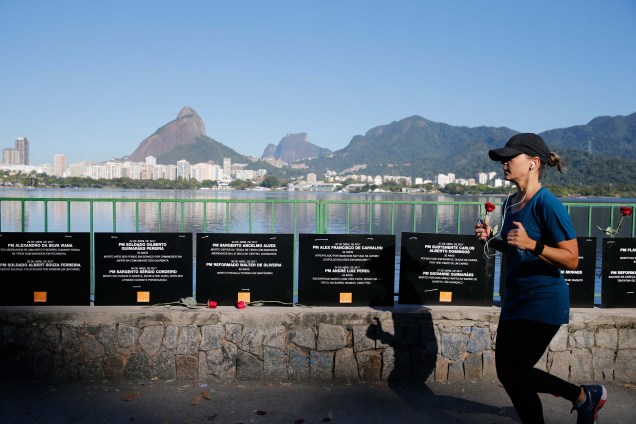Mulher passa correndo na orla da Lagoa Rodrigo de Freitas, em frente a homenagem da ONG Rio de Paz aos policiais militares mortos em serviço este ano no Rio - 25/07/2017