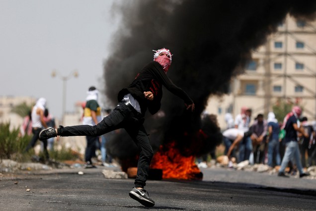 Manifestante palestino lança pedras contra tropas israelenses em confronto nos arredores do assentamento judeu de Beit El, em Ramallah - 24/07/2017