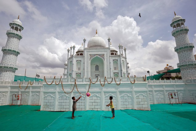 Crianças brincam com uma bola em frente a uma réplica do Taj Mahal construída em Bengaluru, na Índia - 06/07/2017