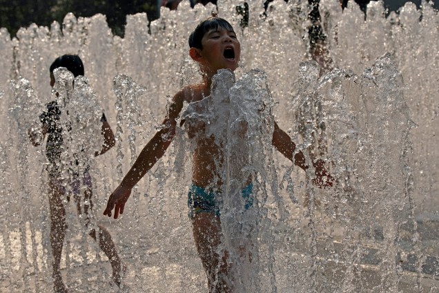 Crianças se refrescam do clima quente em uma fonte em Xangai, China - 21/07/2017