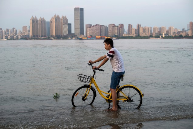 Homem anda de bicicleta nas margens do rio Yangtze em Wuhan, província chinesa de Hubei, após fortes chuvas que provocaram a elevação dos níveis do rio e causaram alagamentos e deslizamentos de terra na região - 03/07/2017