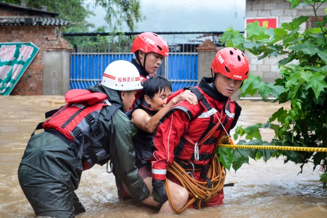 Equipes de resgate ajudam uma idosa a atravessar uma rua inundada em Guilin, na província de Guangxi, na China. Inundações no sul do país mataram 15 pessoas nos últimos dias e obrigaram milhares de pessoas a evacuar suas casas - 03/07/2017