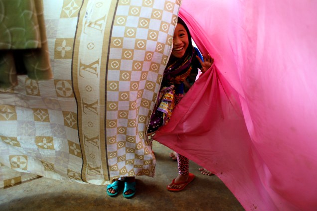 Garota brinca com lençois que separam quartos de famílias em um acampamento improvisado em Marawi, nas Filipinas, após tropas do governo e terroristas entrarem em confronto na cidade - 07/07/2017