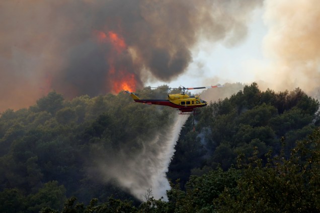 Um helicóptero do corpo de bombeiros despeja água sobre as chamas de um incêndio florestal em Carros, perto de Nice na France - 24/07/2017