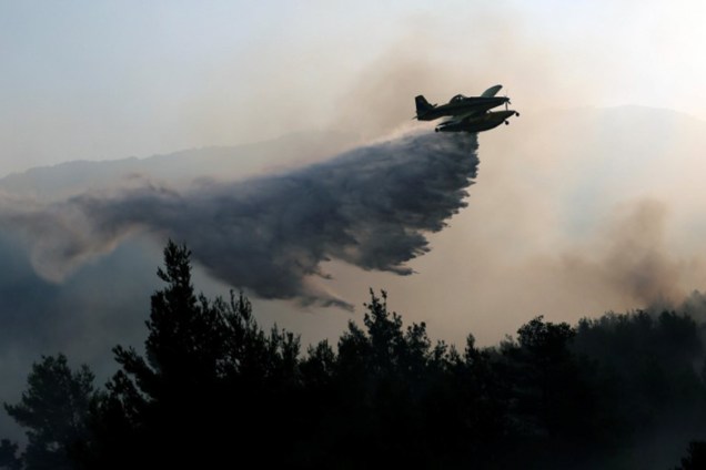Avião de combate a incêndios joga água para apagar fogo no vilarejo de Stobrec, perto de Split, na Croácia - 18/07/2017